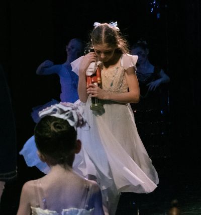 Young girl holding a nutcracker on stage.