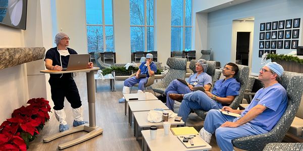 picture of surgeons listening to another surgeon give a presentation on laptop in a large room