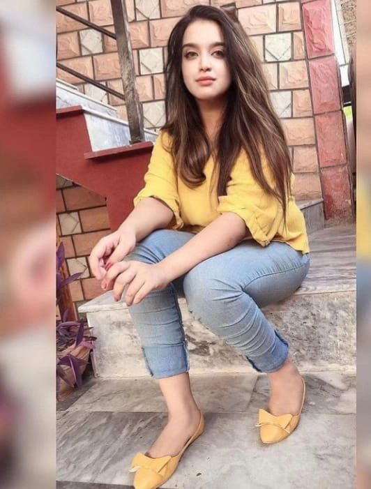 Young woman in yellow top and blue jeans sitting on stairs.