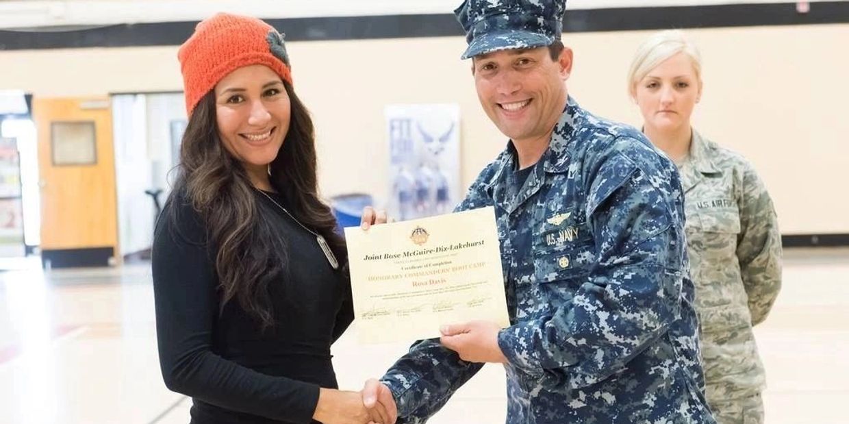 Woman receiving certificate from Navy officer, another military person in background.