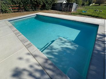 Clear, inviting outdoor swimming pool with steps and surrounding patio.