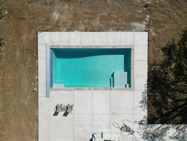 Aerial view of a rectangular pool with two lounge chairs nearby.