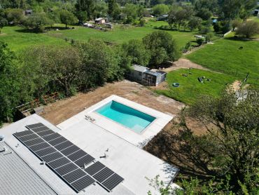 A backyard with a swimming pool and solar panels on the roof.