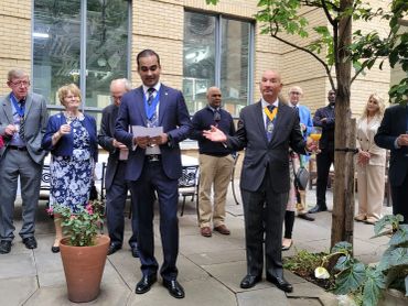 Two men in suits speak at an outdoor gathering.