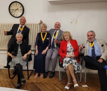 Group of six adults celebrating with medals and drinks.