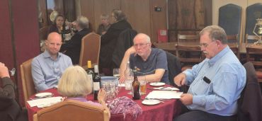 Four people seated around a dining table in a formal setting.