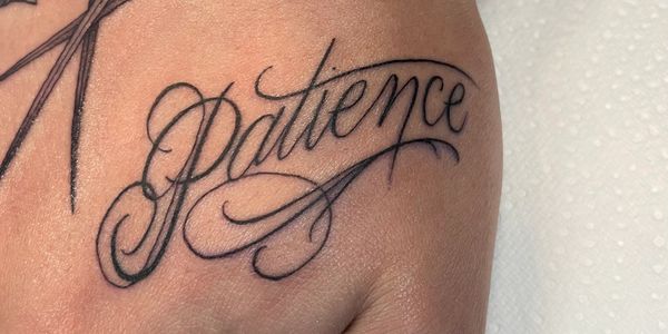 Fine line script tattoo of a word Patience on a hand