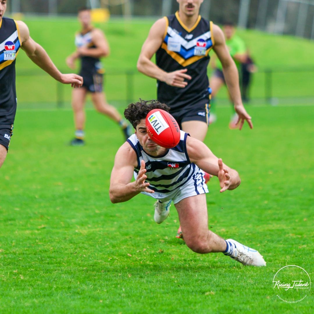 Australian football player diving for the ball.