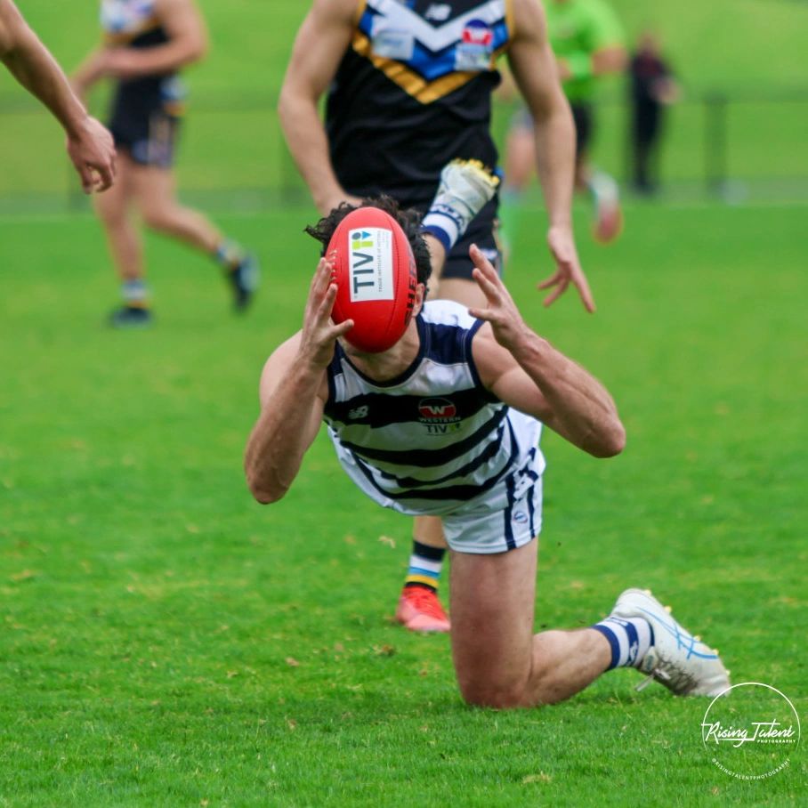 Player catching a football mid-air on a grassy field.