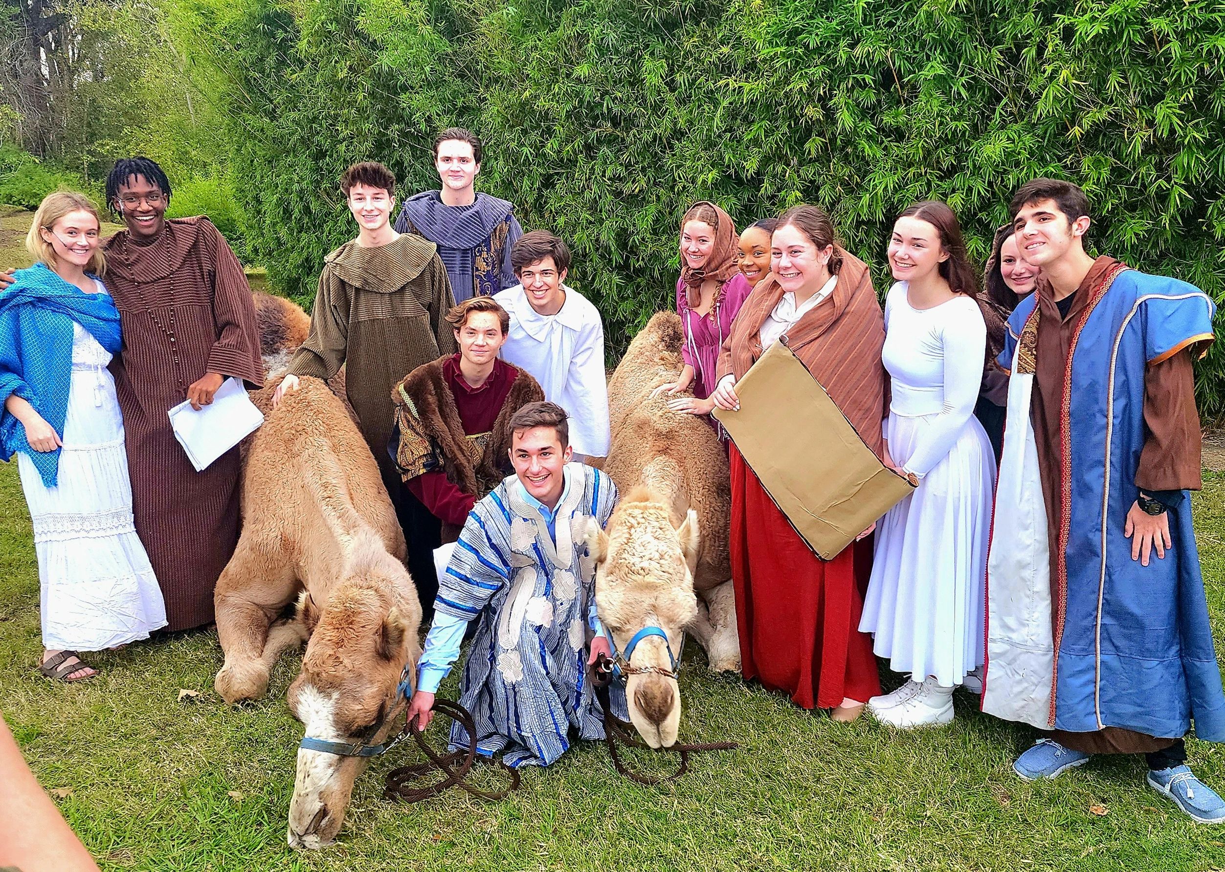 Camel and actors in costume posing for a group photo after a live nativity play