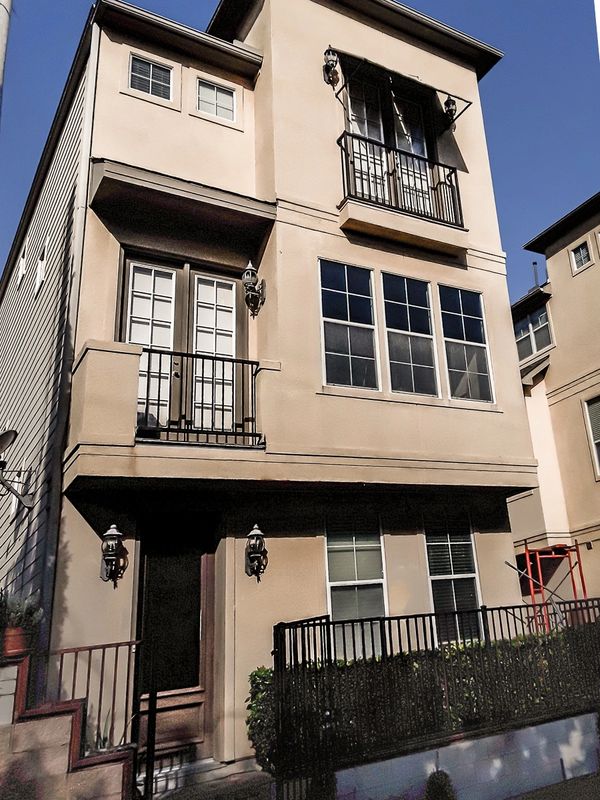 Townhome before stucco facade remodel. Stucco is dirty and there are some ledge lines. Left view.