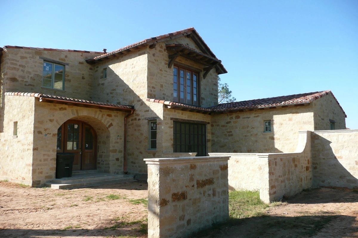 A house made of stone with stone surrounding walls and accents. The stone has a blend of colors.