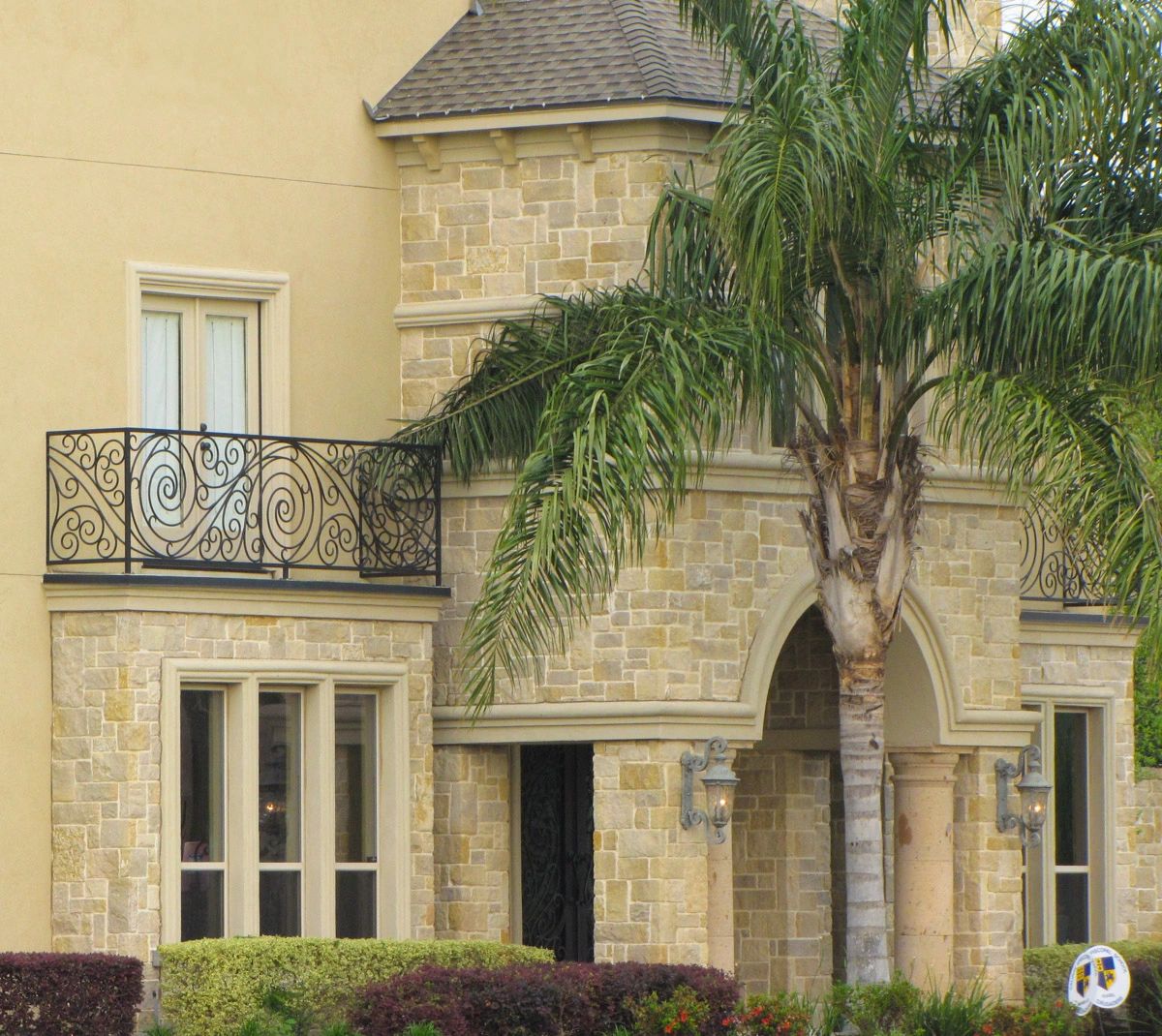 Part of a luxurious house with stone, cast stone and stucco on its facade, with a balcony