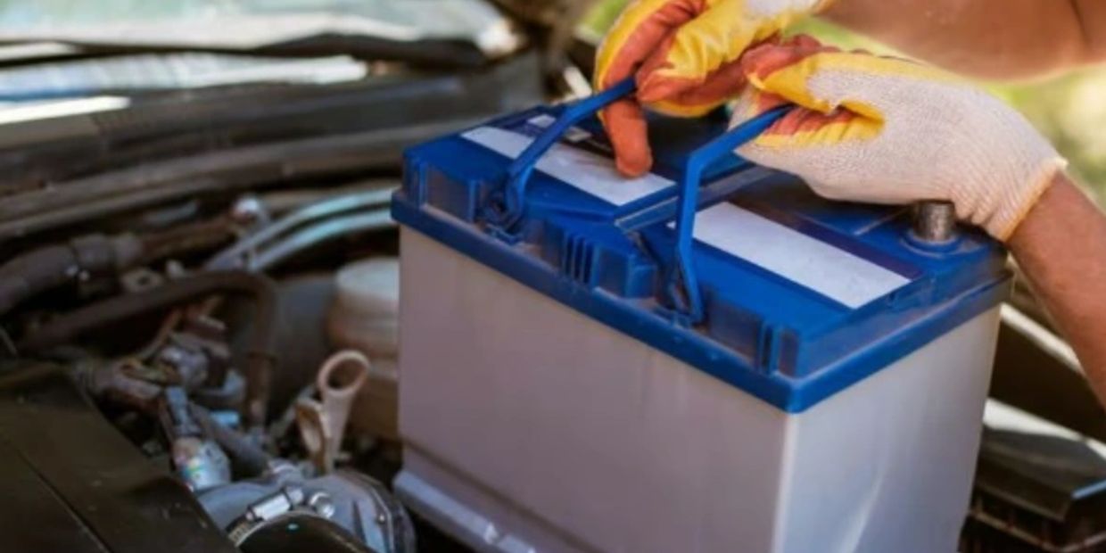 Person removing a car battery from an engine.