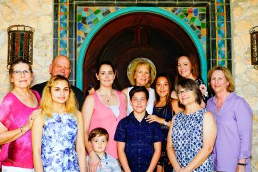 A diverse family group posing together in front of a decorative door.