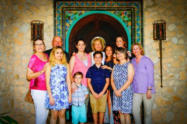 A group of people posing in front of a stone wall and decorative door.