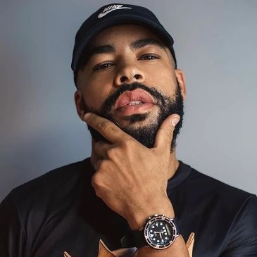 Bearded man in a black Nike cap and watch posing thoughtfully.