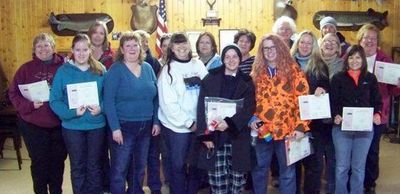 Group of people holding certificates in a rustic indoor setting.