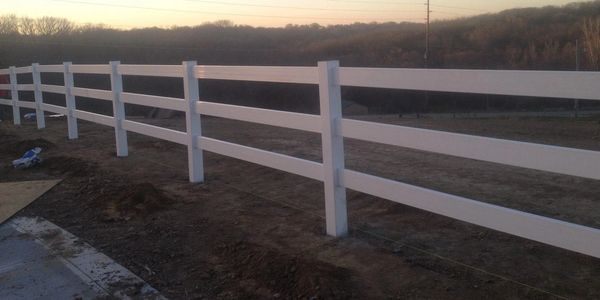 White wooden fence stretching across a rural landscape at sunset.