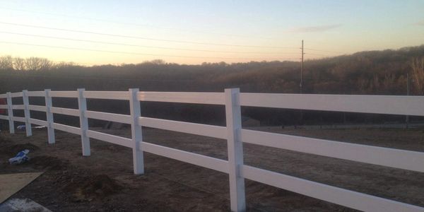 White wooden fence stretching across a rural landscape at sunset.