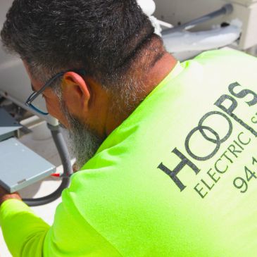 Worker in neon shirt fixing electrical box.