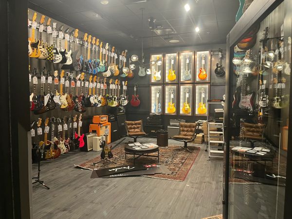 A cozy guitar showroom with various electric guitars and seating area.