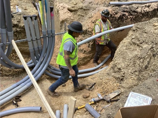 Two construction workers installing underground pipes at a worksite.
