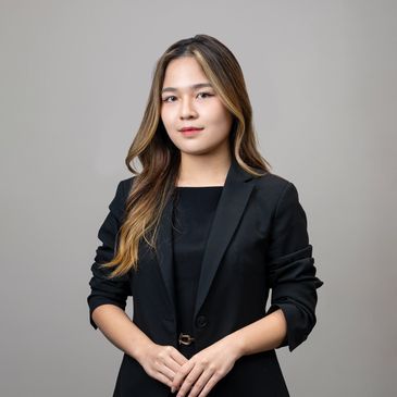 Professional woman in black blazer against gray background.