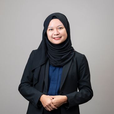 Woman in a black hijab and blazer smiling.