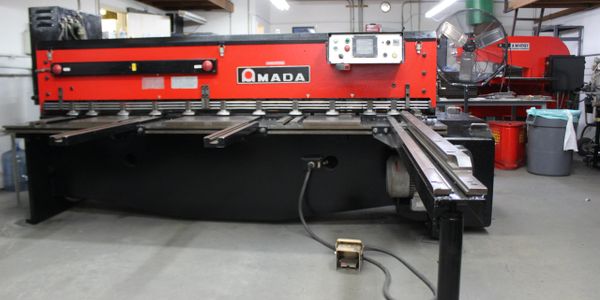 Large red Amada industrial metal cutting machine in workshop.