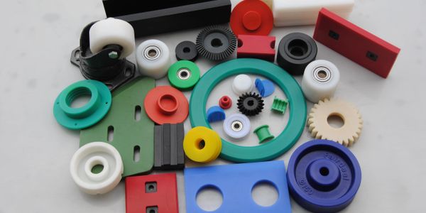 Colorful plastic and rubber mechanical parts arranged on a white surface.