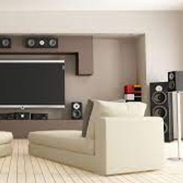 Modern living room with beige sofas and a large TV setup.