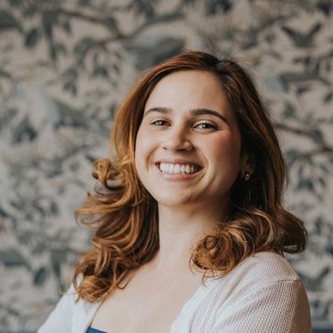 Smiling young woman with curly hair and a friendly expression.