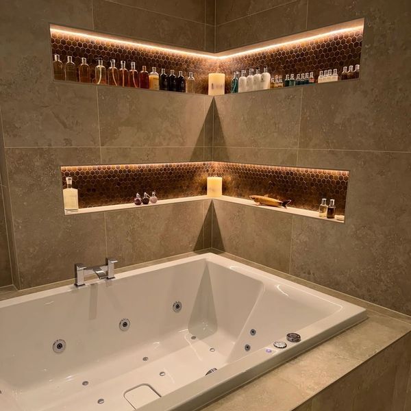 Luxurious bathtub with ambient lighting and neatly arranged bottles.