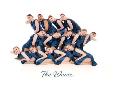 A group of dancers in blue outfits posing in a wave formation.