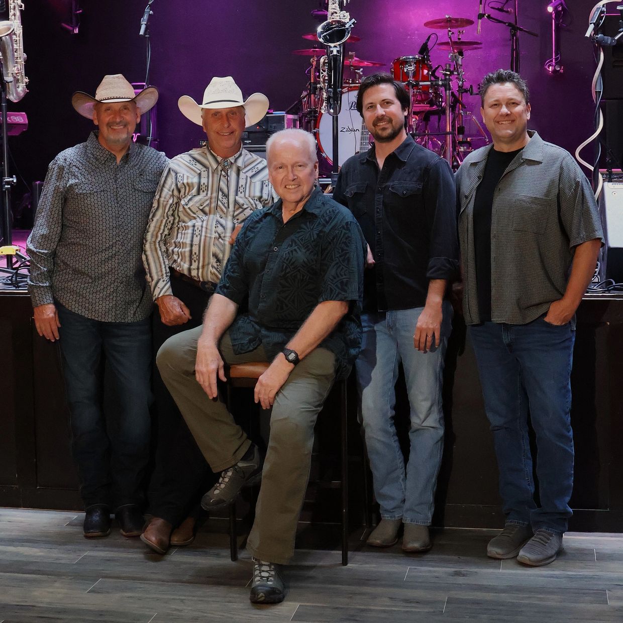 Group photo of five men in a music venue.
