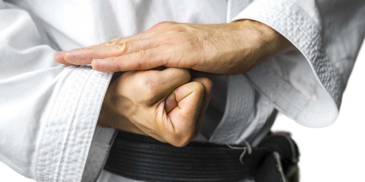 A person with a black belt holding his fist 