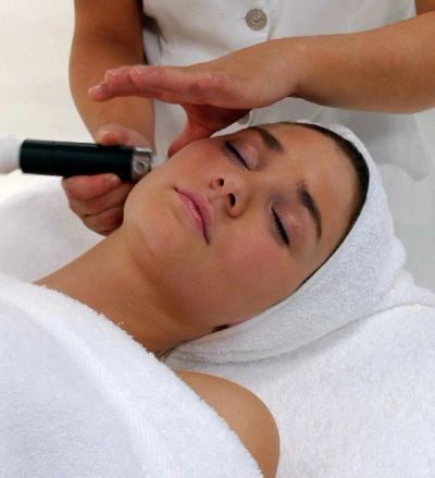Woman receiving a facial treatment with a device at a spa.