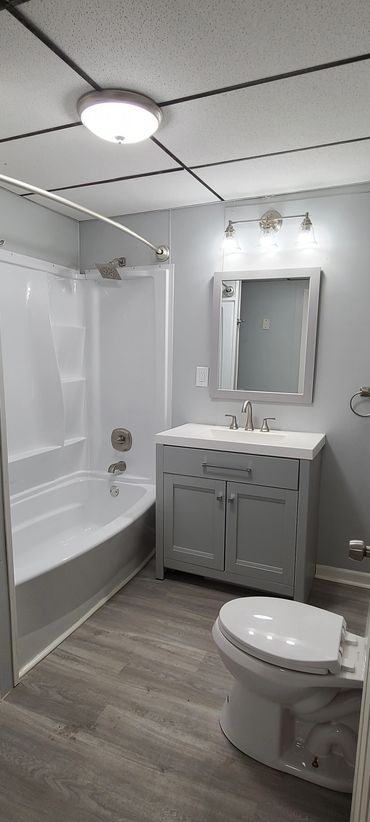 Clean modern bathroom with bathtub, vanity, and toilet.