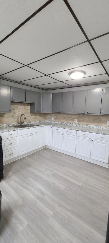 Modern kitchen with gray and white cabinets and light flooring.