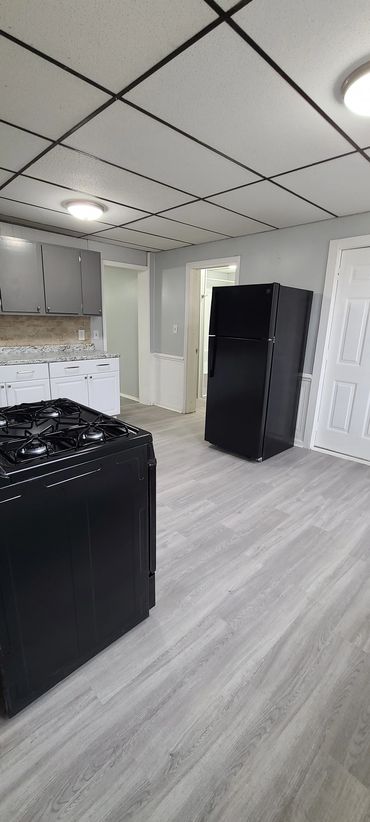 Modern kitchen with black appliances and light grey flooring.