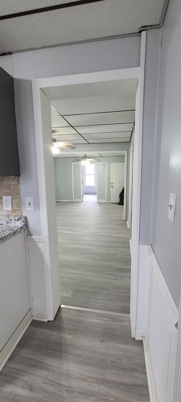 Empty room with light gray flooring and ceiling fans.
