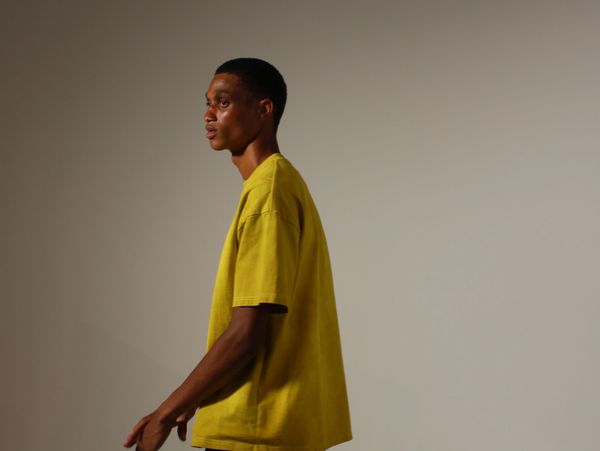 A model posing for a New york fashion week photoshoot, wearing a yellow t shirt 
