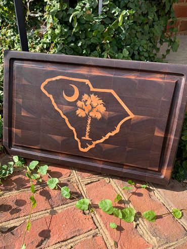 Walnut end-grain cutting board.  It has been inlayed with maple in the shape of South Carolina.