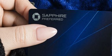 Hand holding a Sapphire Preferred credit card with a blue design.