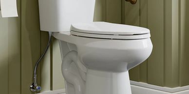 A white toilet installed in a green paneled bathroom corner.