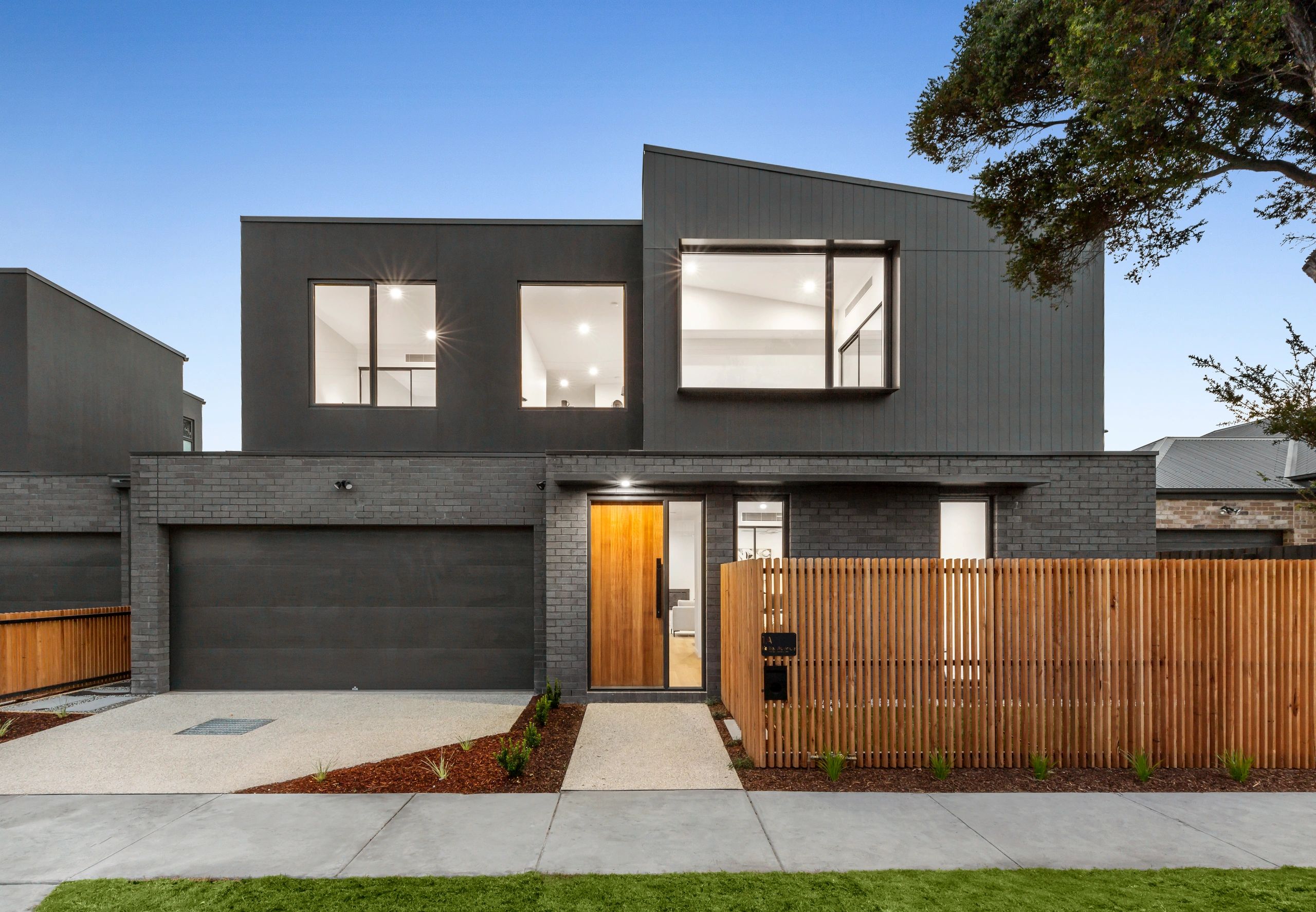 Modern two-story house with dark exterior and wooden fence.