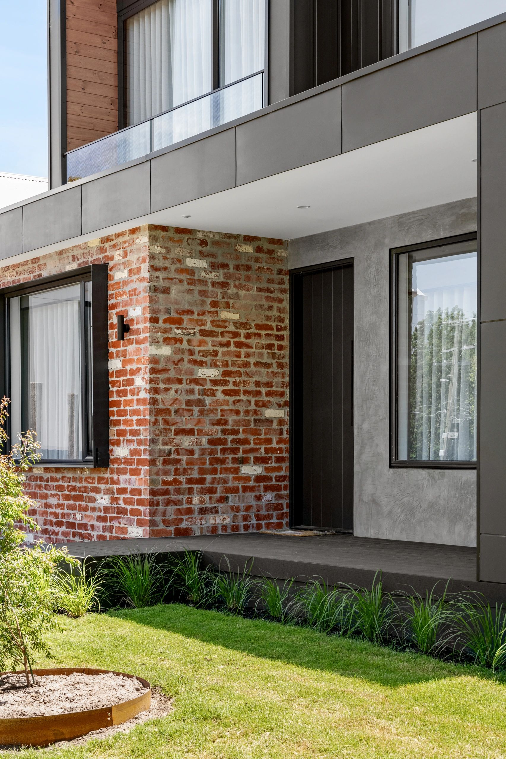Modern house exterior with brick, concrete, and glass elements.
