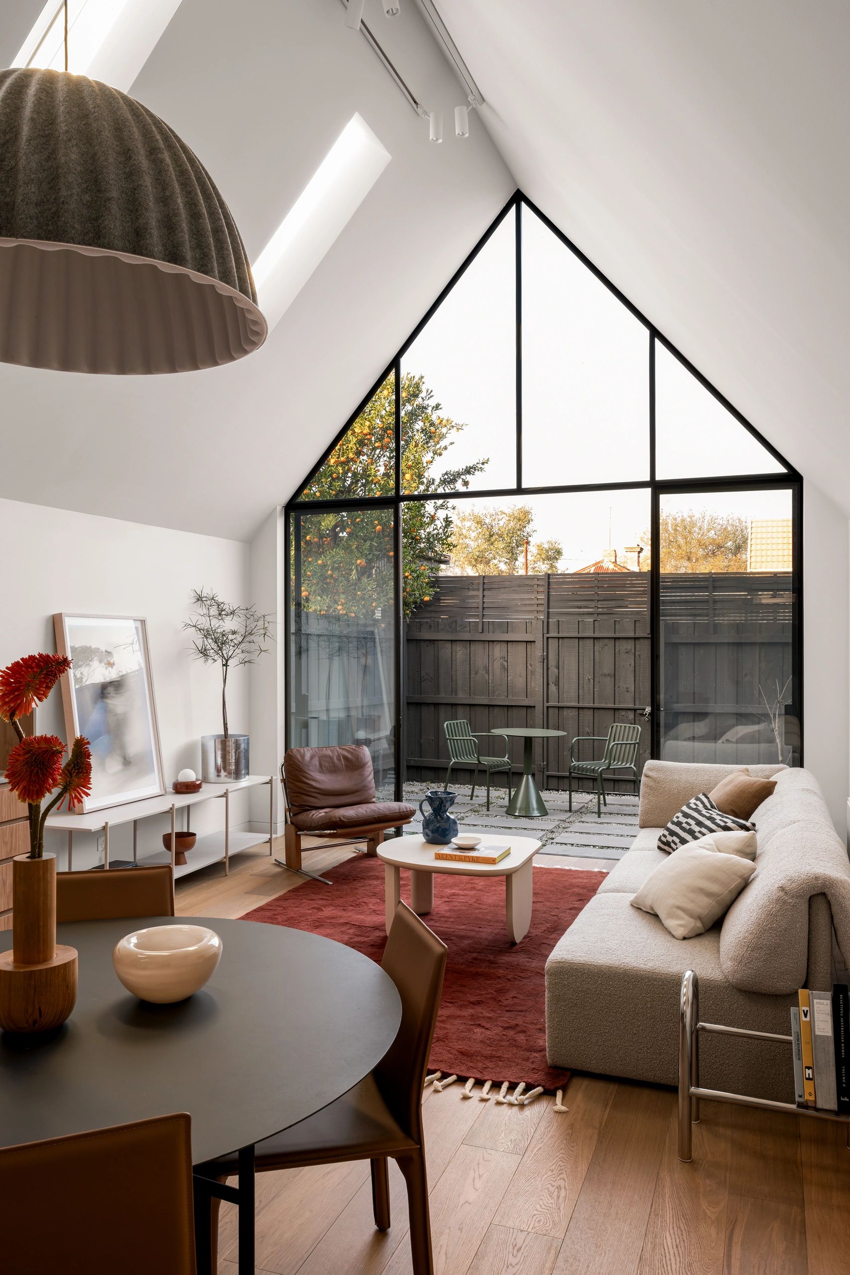 Modern living room with high window and cozy seating.