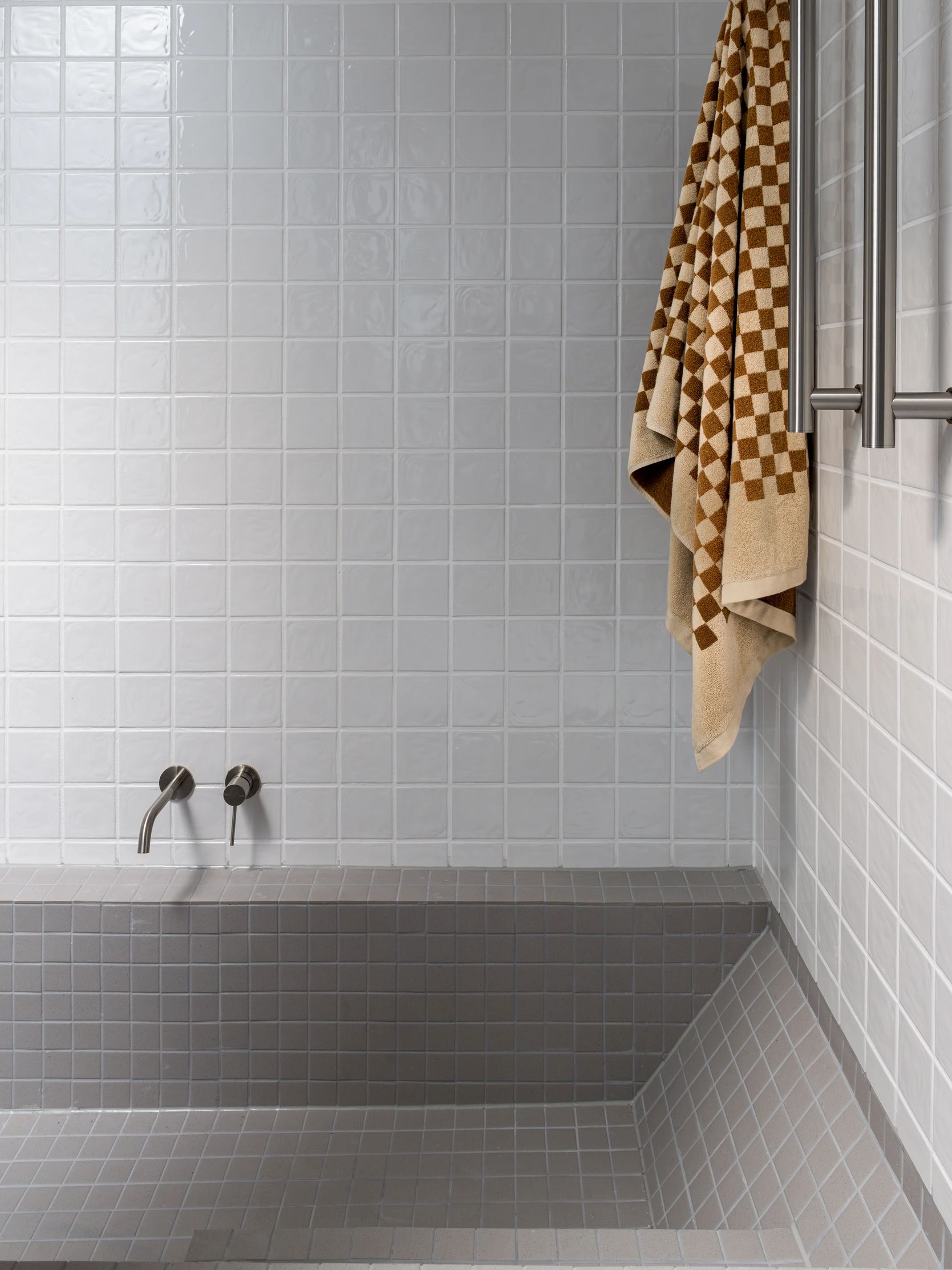 Modern tiled shower with towel and fixtures.